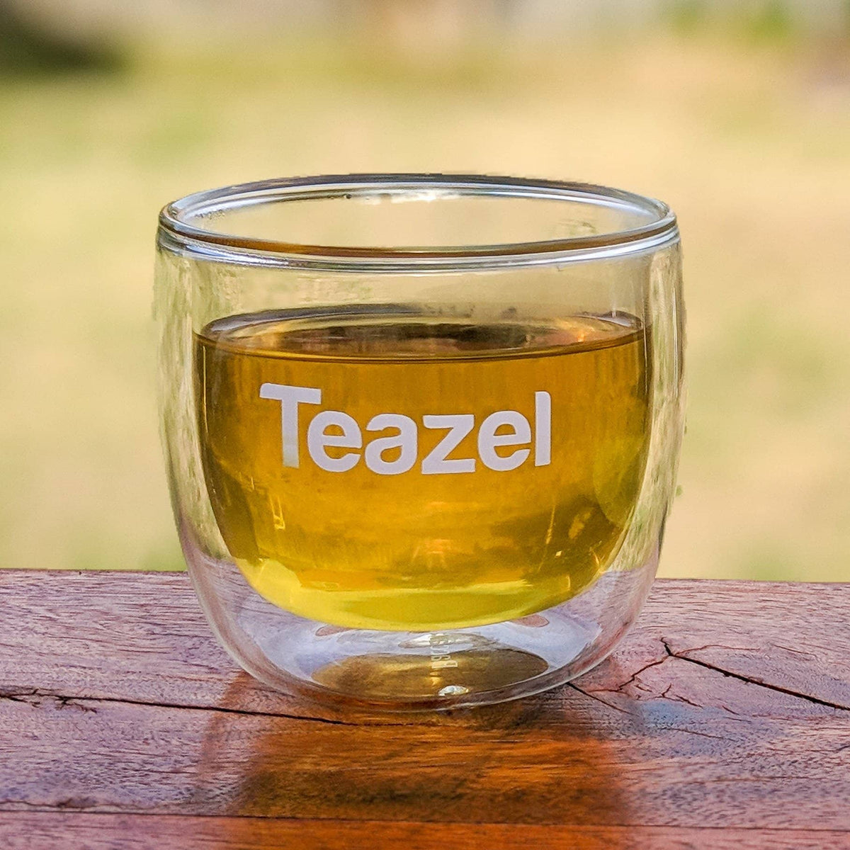 White &#39;Teazel&#39; lettering logo decal on a small glass.